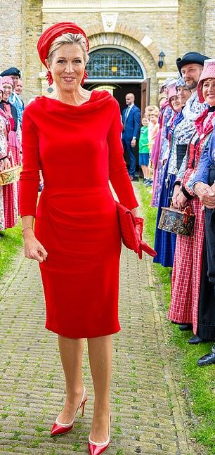 Королева улыбнулась, чтобы сделать фото рядом с местными жителями в традиционной голландской одежде